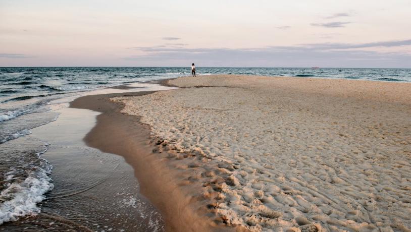 Kvinne som står på stranden på Grenen i Skagen i Danmark