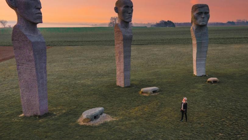 Person looking at stone sculptures Dodekalitten during sunset on Lolland-Falster, Denmark