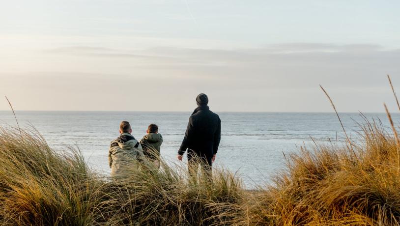 Familie kijkt naar de zee bij Blåvand strand, West-Jutland