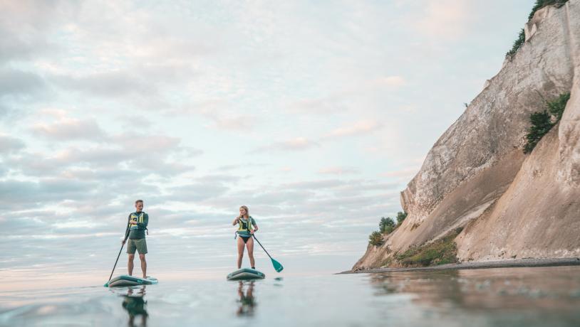 Two people paddle on a Stand up paddle board