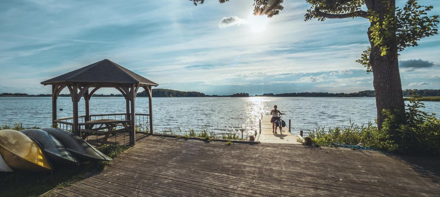 Fahrradfahrerin steht am See im Maribo Naturpark, Lolland-Falster