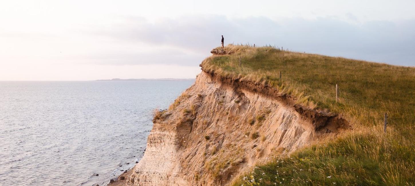 Person standing at the Limfjord on a cliff, Denmark