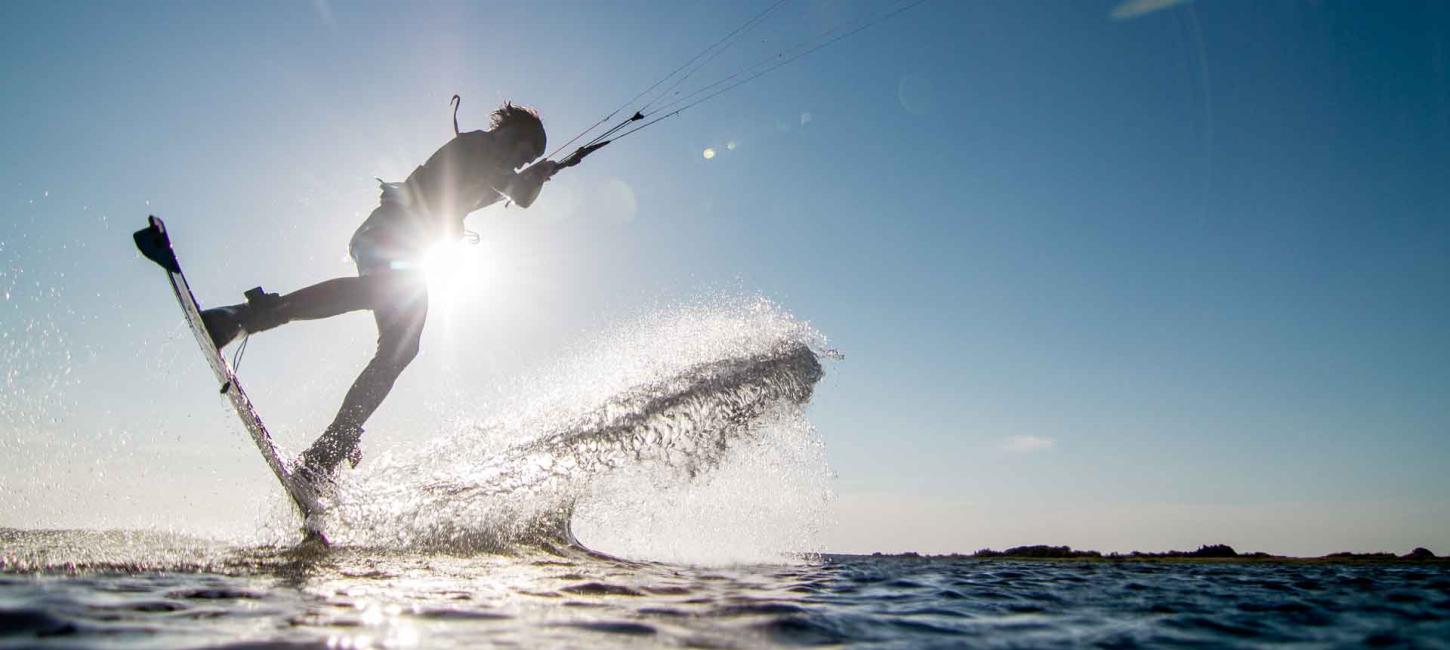 Ein Kite-Surfer fliegt dynamisch über die Wellen an der Küste Dänemarks beim WATERZ-Wassersportfestival