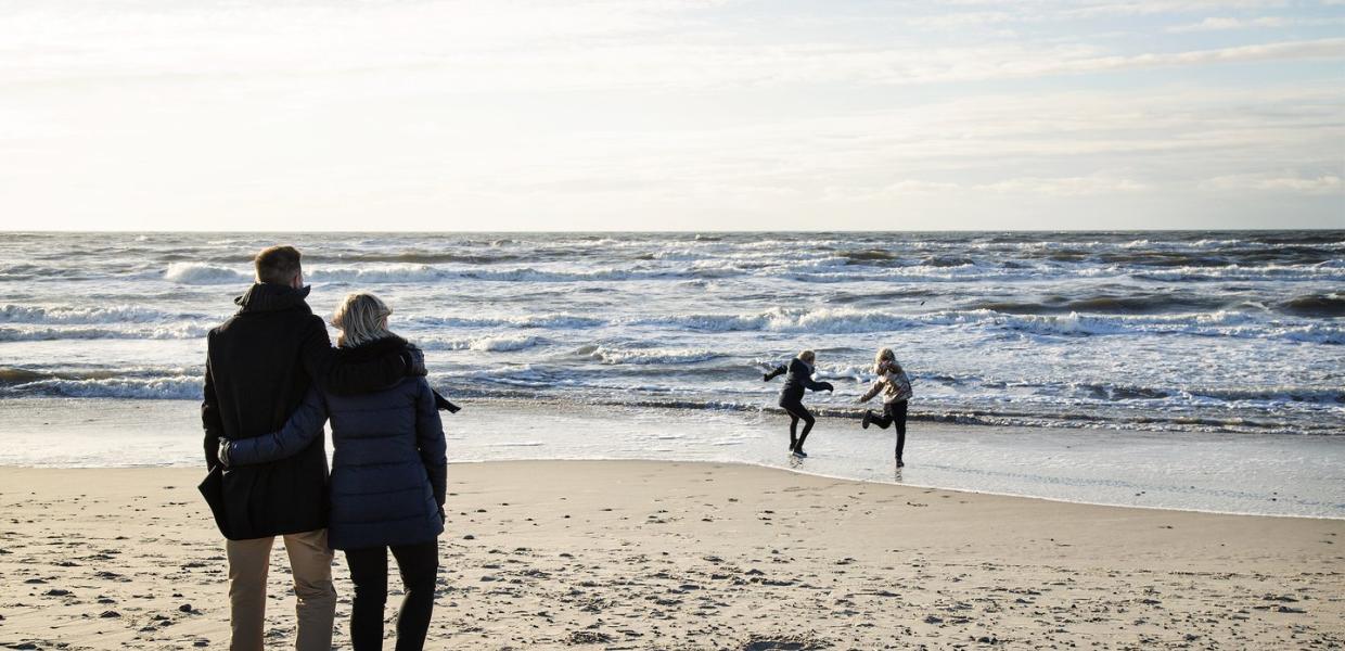 Foreldre og barn leker på standen på høsten i Søndervig, Vesterhavet, Danmark