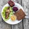 Tallerken med klassisk dansk smørrebrød med sild og frikadelle på et bord