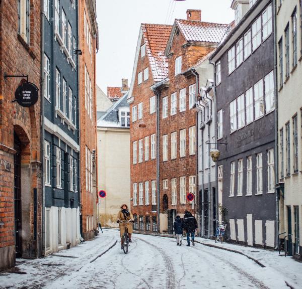 A woman cycles down snowy Magstræde in Copenhagen, Denmark