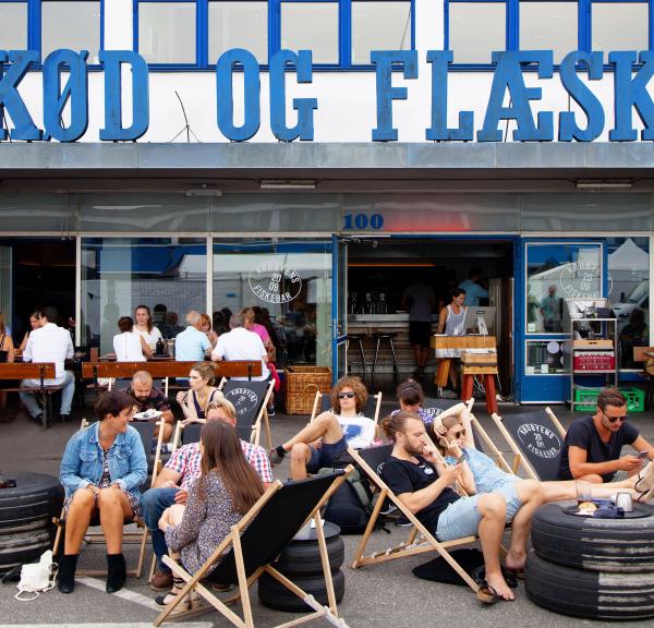 People sitting on sun chairs outside an old butchers building in the meatpacking district