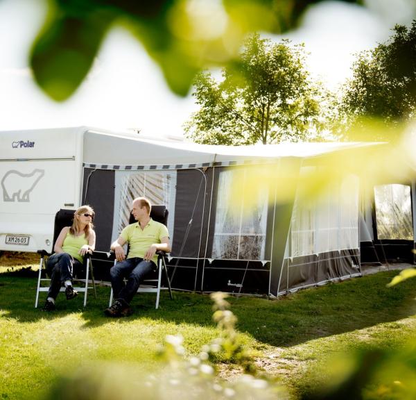 2 people sitting in front of a caravan