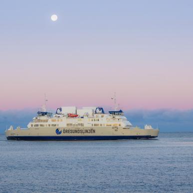 Öresundslinjens färja i horisonten som kryssar över havet vid solnedgång.